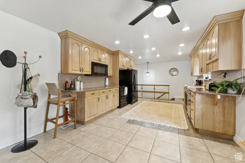 Kitchen with black appliances, light brown cabinetry, light stone countertops, a ceiling fan, and recessed lighting
