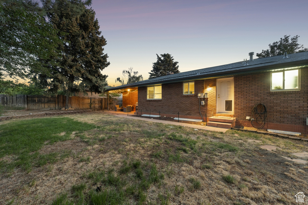 Back of house at dusk featuring brick siding