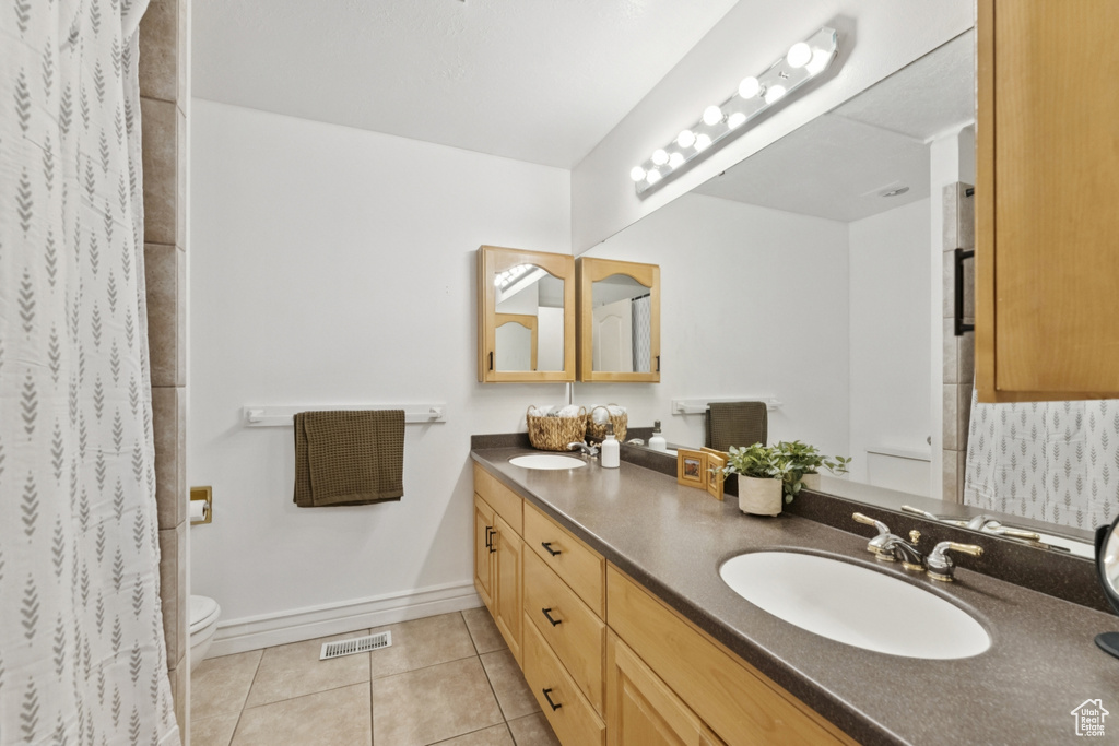 Full bath with double vanity, tile patterned flooring, and a shower with shower curtain