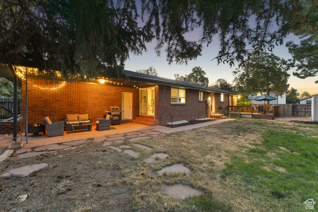 Rear view of property with an outdoor living space, brick siding, a deck, and a patio area