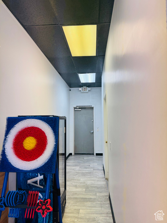 Hallway with light wood-type flooring and a paneled ceiling