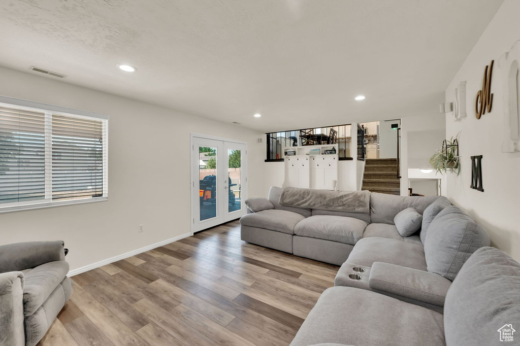 Living room with recessed lighting, light wood-style floors, french doors, and stairway