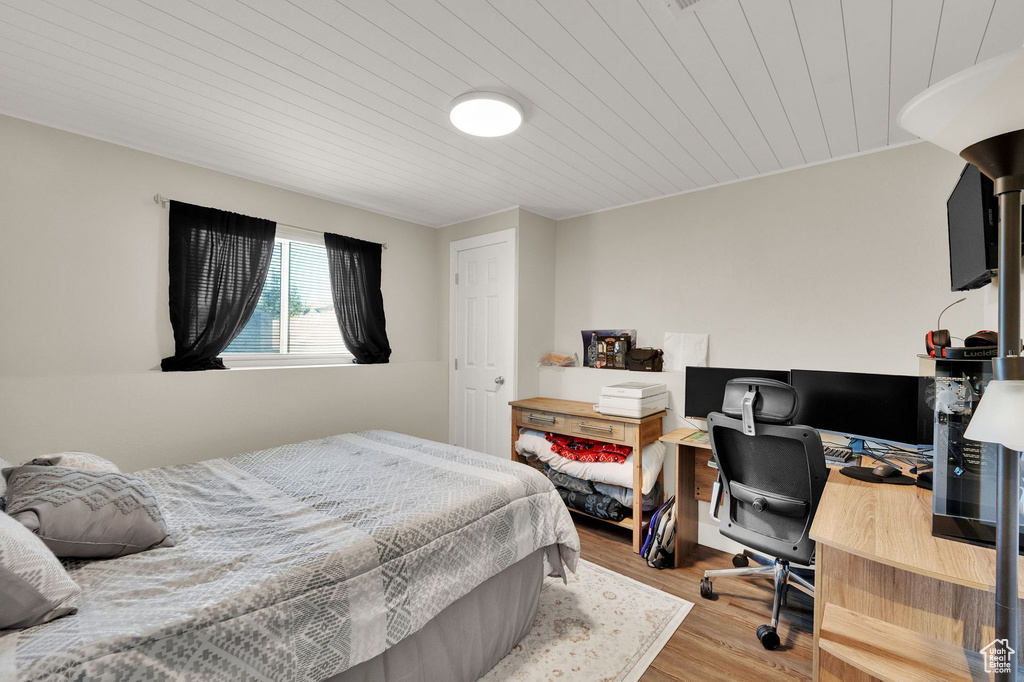 Bedroom with wood ceiling, wood finished floors, and an office area