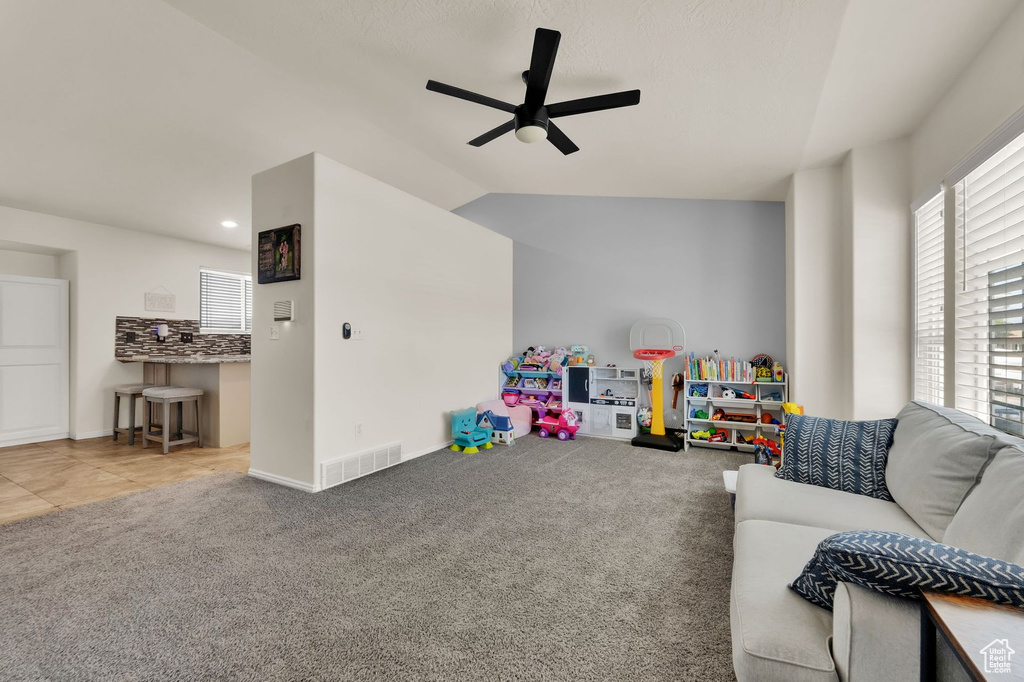 Recreation room with ceiling fan, plenty of natural light, carpet floors, and vaulted ceiling