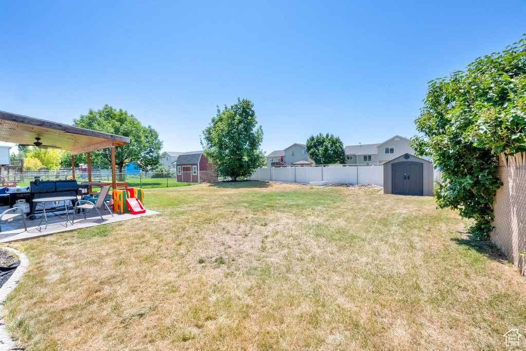 Fenced backyard with a shed, ceiling fan, and a patio