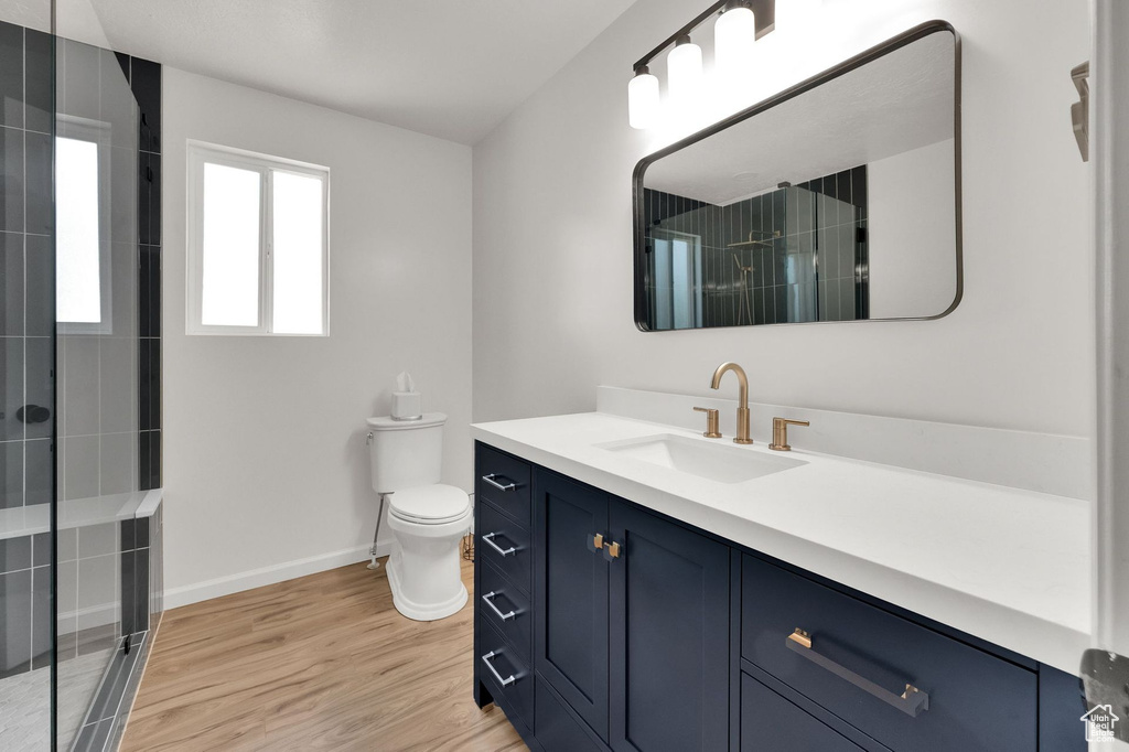Bathroom featuring vanity, a tile shower, and wood finished floors