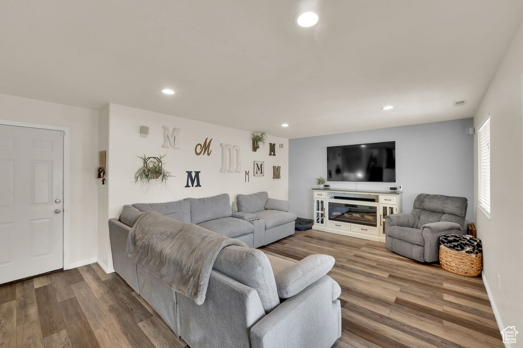 Living area featuring dark wood finished floors, recessed lighting, and a glass covered fireplace