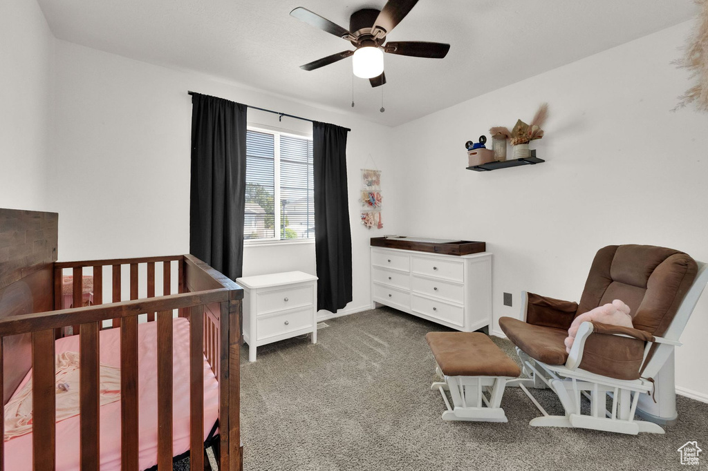 Bedroom featuring carpet flooring, a crib, and a ceiling fan