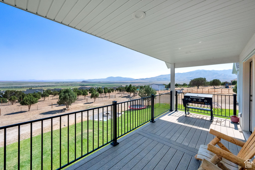 Wooden terrace featuring a mountain view and a lawn