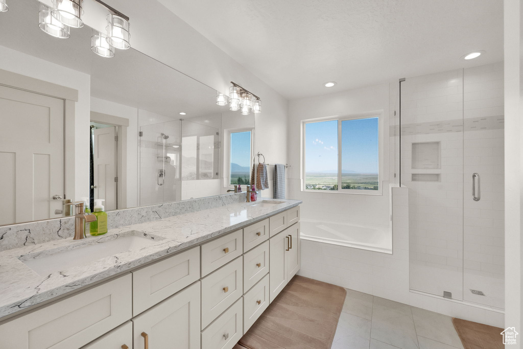 Full bath featuring double vanity, a shower stall, a garden tub, tile patterned floors, and recessed lighting