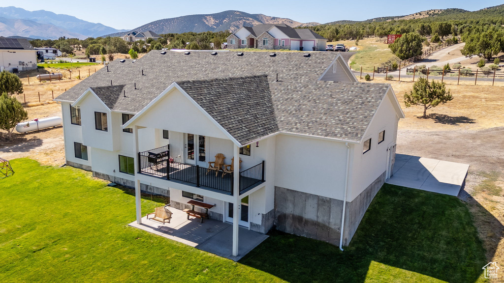 Back of property featuring a patio, a yard, a mountain view, and stucco siding