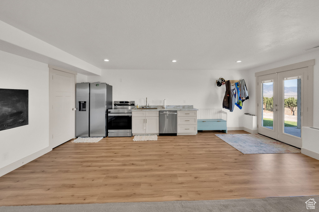 Kitchen featuring appliances with stainless steel finishes, light wood-style floors, white cabinets, light countertops, and recessed lighting