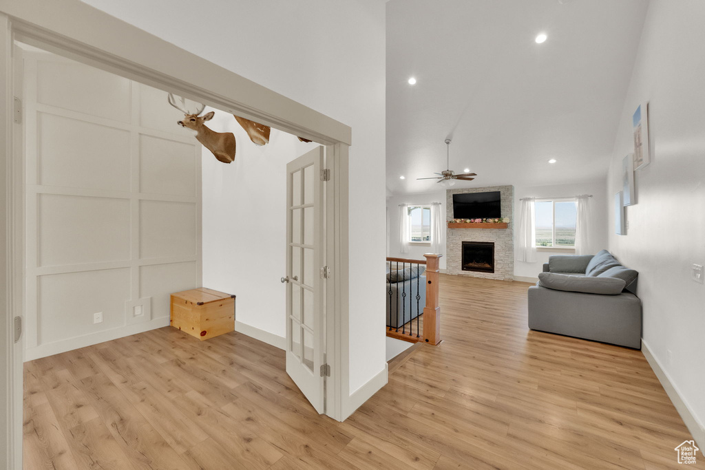 Living area featuring a fireplace, light wood-style flooring, a ceiling fan, recessed lighting, and high vaulted ceiling