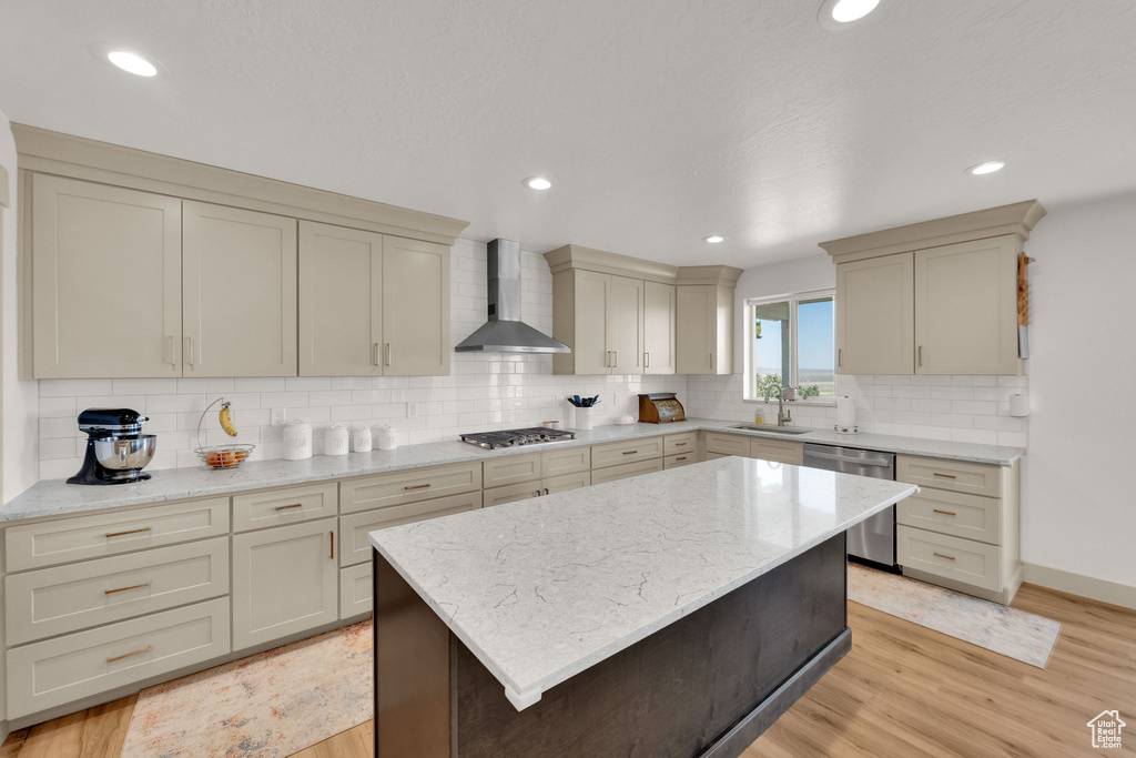 Kitchen with wall chimney exhaust hood, stainless steel appliances, light wood finished floors, decorative backsplash, and recessed lighting