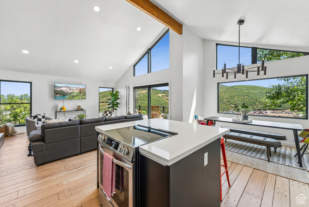 Kitchen featuring stainless steel range with electric stovetop, light wood-style flooring, beamed ceiling, a center island, and high vaulted ceiling