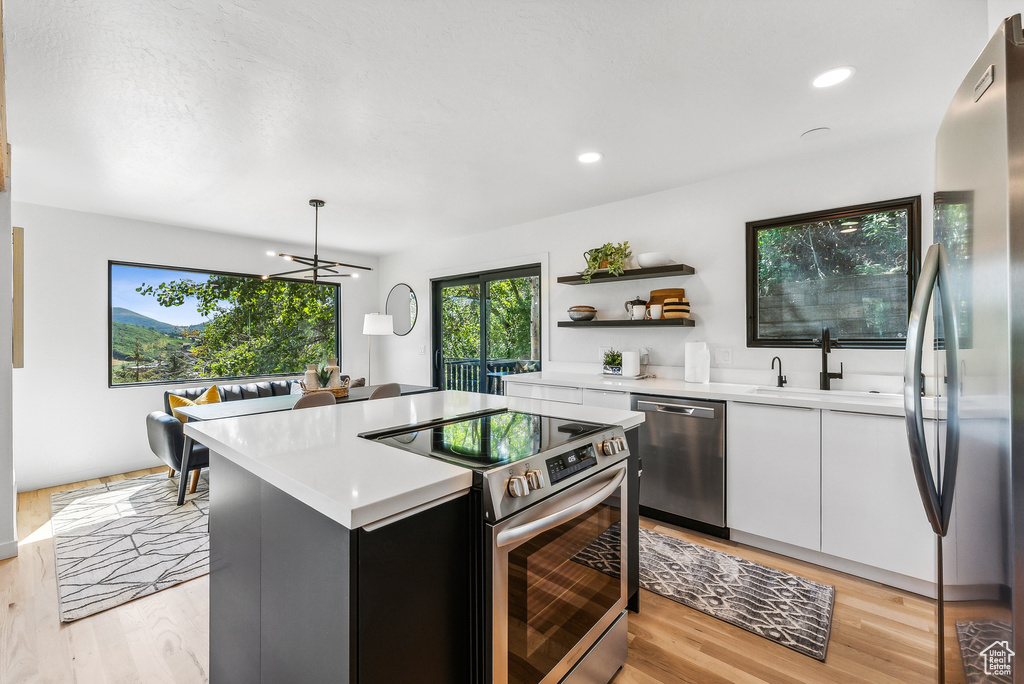 Kitchen featuring stainless steel appliances, light countertops, white cabinets, open shelves, and recessed lighting
