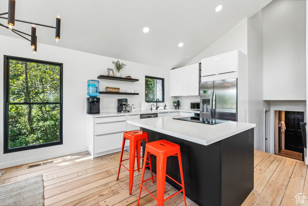 Kitchen featuring stainless steel appliances, white cabinetry, light countertops, light wood finished floors, and open shelves