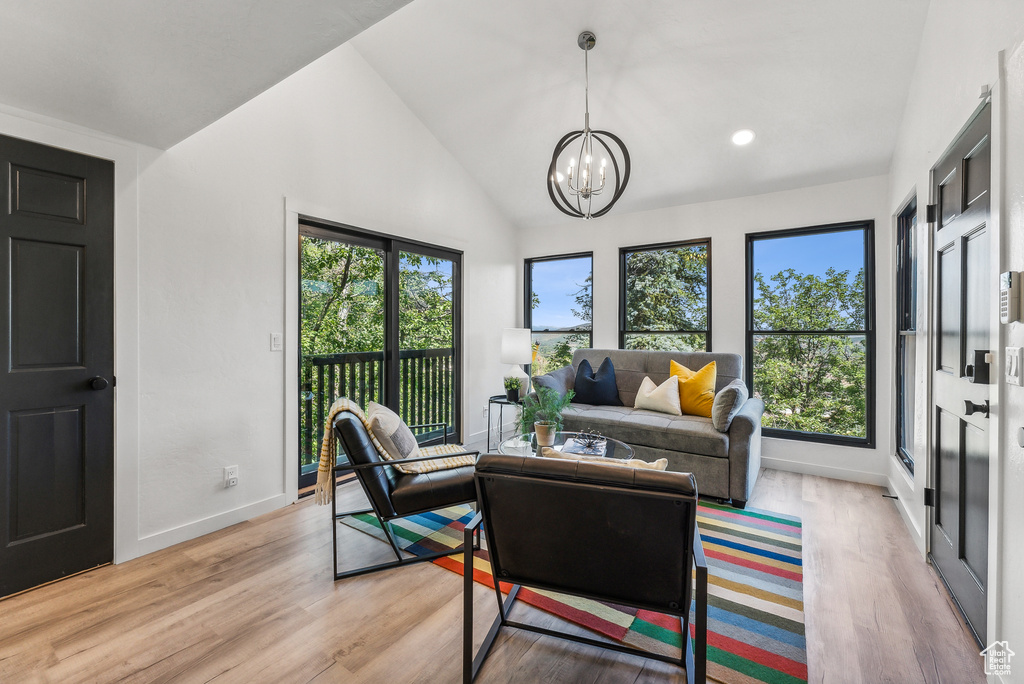 Living room with a chandelier, light wood-type flooring, and high vaulted ceiling