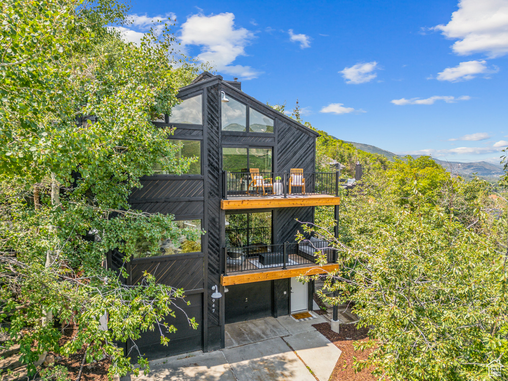 Rear view of property featuring a sunroom, driveway, a mountain view, and a garage