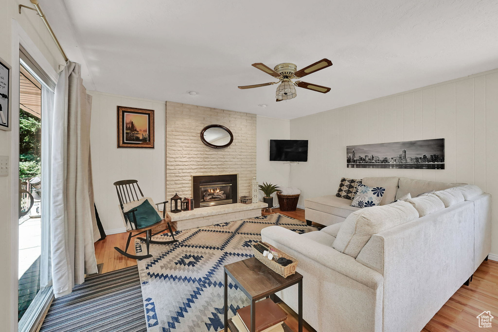 Living room with ceiling fan, wood finished floors, and a fireplace