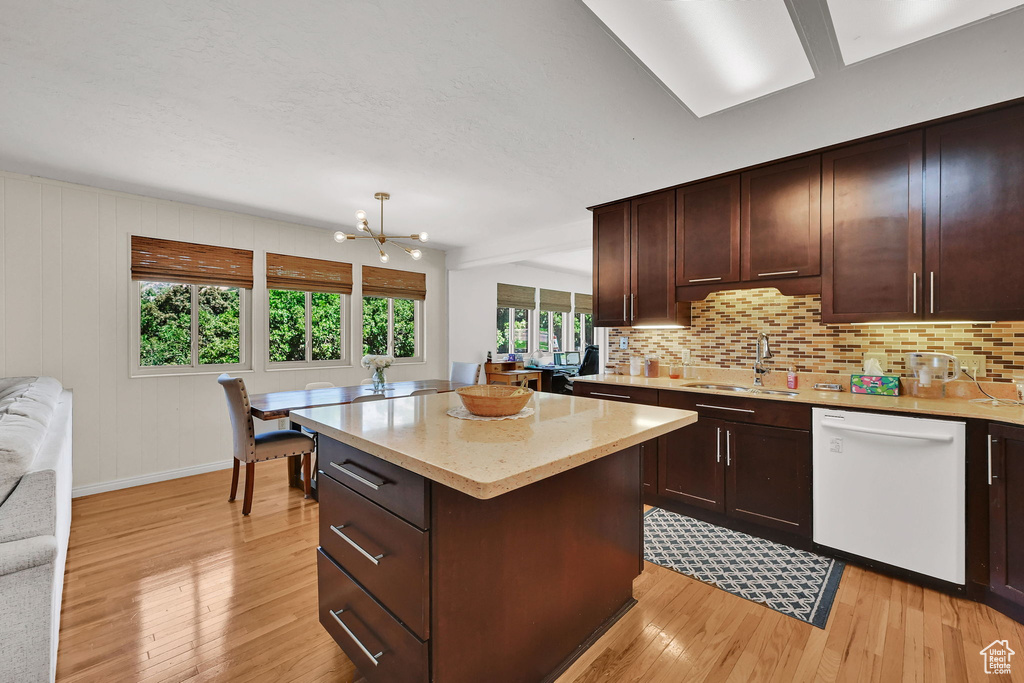 Kitchen with dishwasher, light wood-style floors, a chandelier, and decorative backsplash