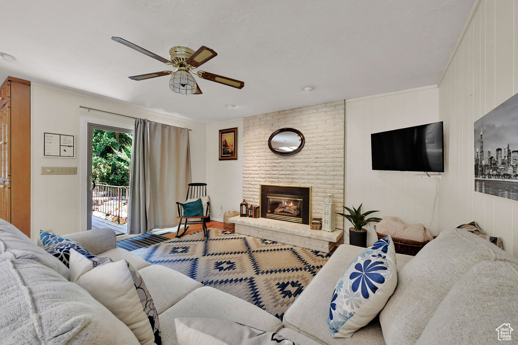Living area featuring a ceiling fan, wood finished floors, and a brick fireplace