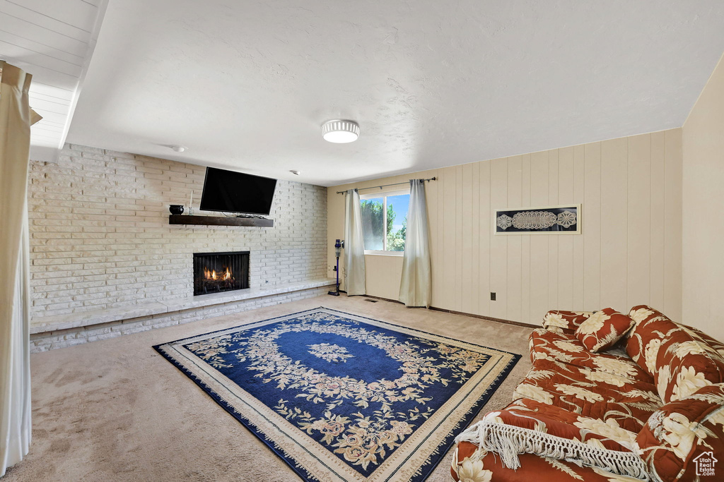 Carpeted living room featuring a fireplace and wooden walls