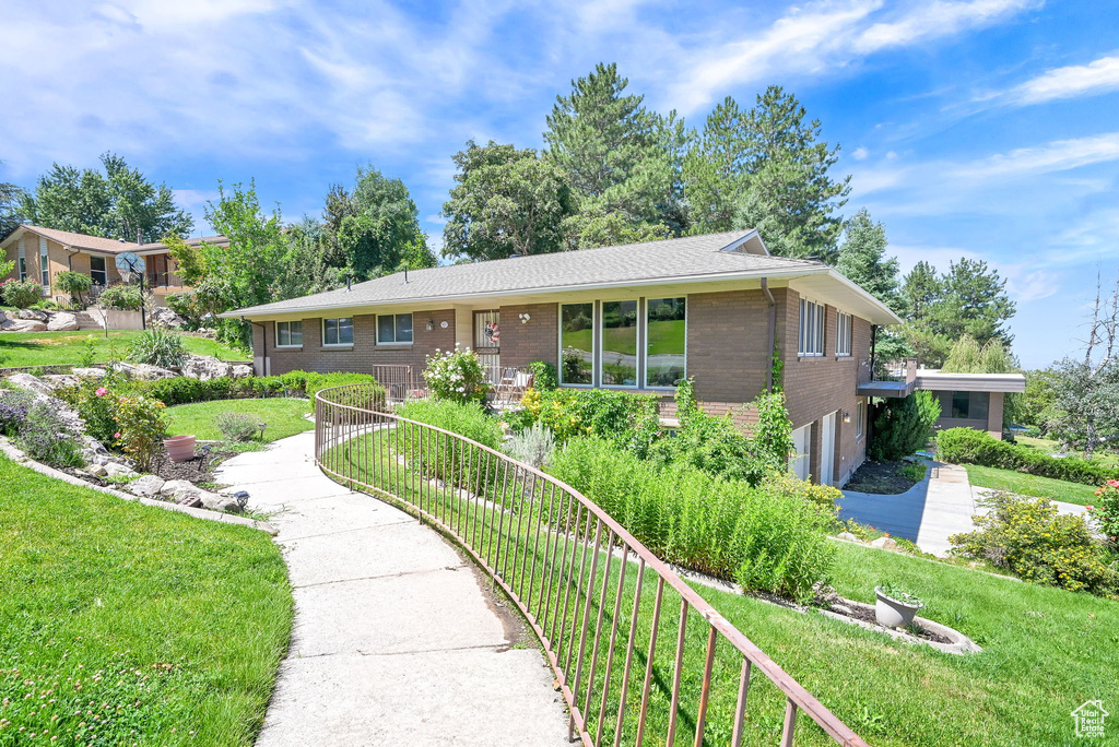 Ranch-style house featuring brick siding, an attached garage, and a front yard