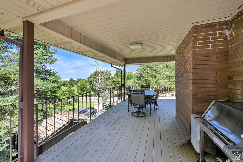 Wooden terrace with outdoor dining area and view of wooded area