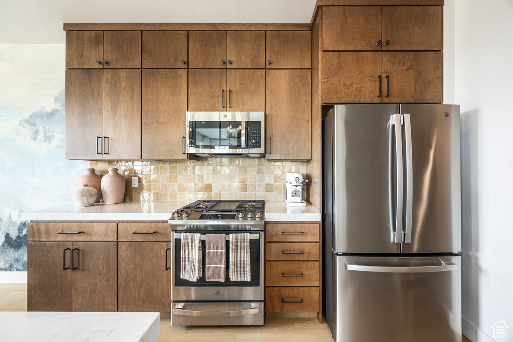 Kitchen with appliances with stainless steel finishes, light countertops, and backsplash