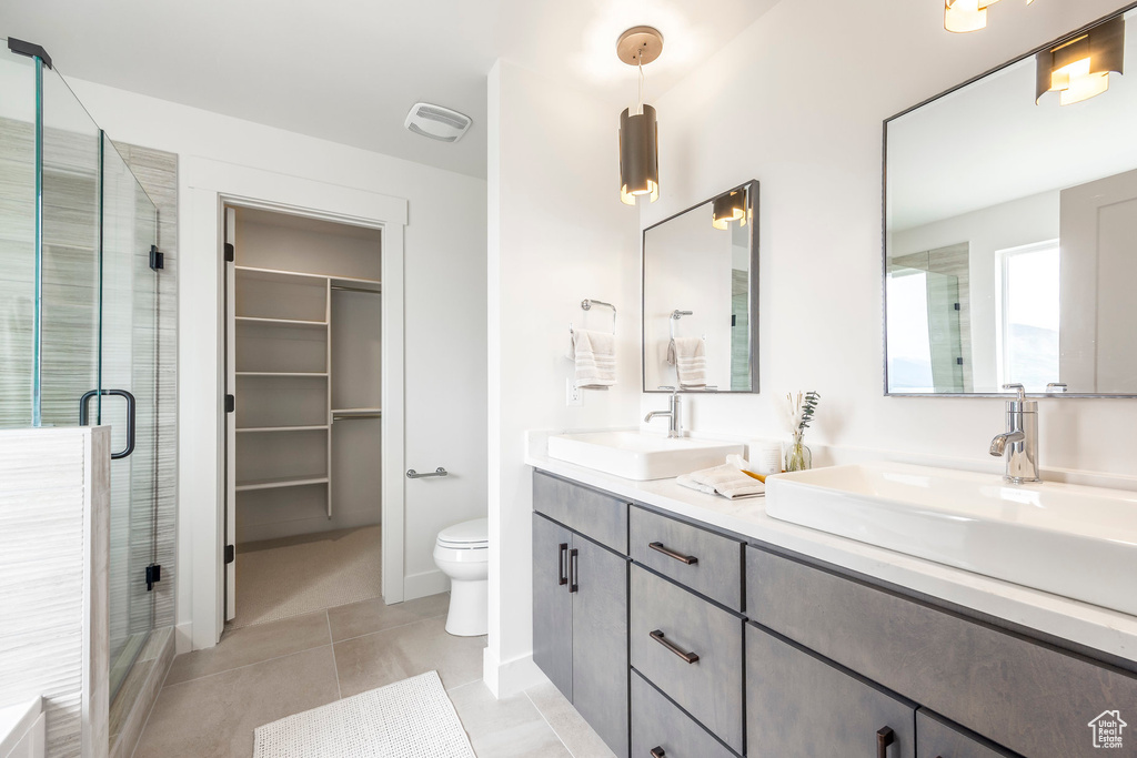 Bathroom featuring double vanity, a shower stall, tile patterned flooring, and a spacious closet