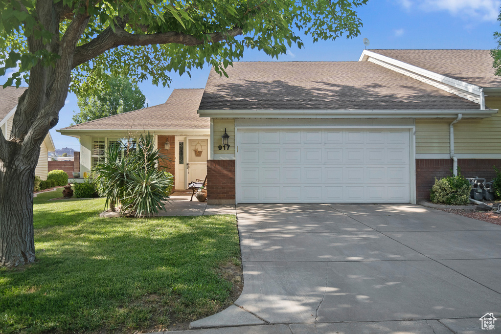 Ranch-style home with concrete driveway, a garage, a front lawn, brick siding, and roof with shingles