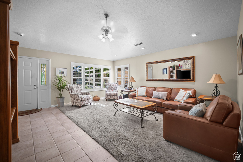 Carpeted living room featuring a textured ceiling, tile patterned flooring, ceiling fan, and recessed lighting
