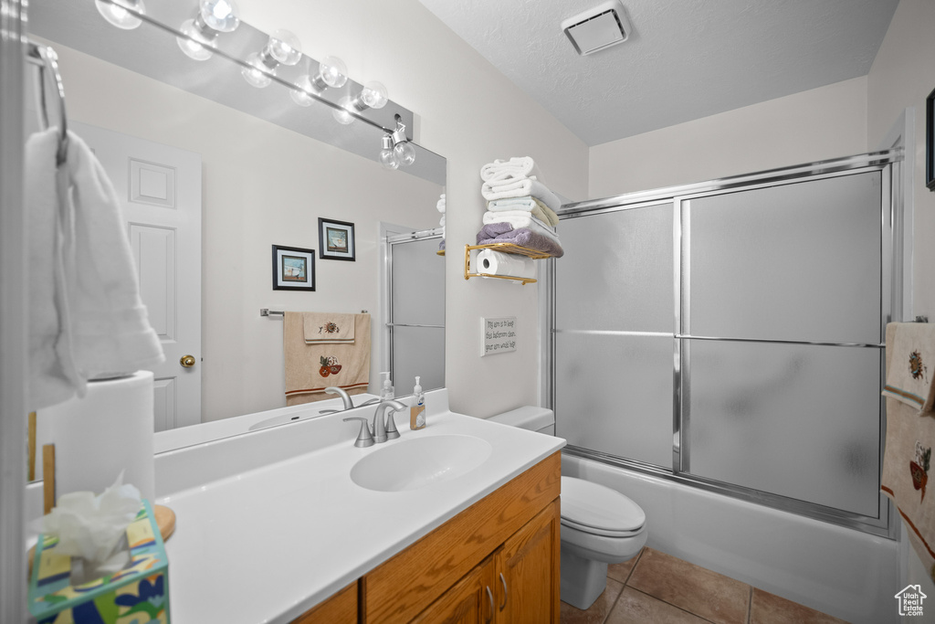 Full bath featuring vanity, bath / shower combo with glass door, and tile patterned floors