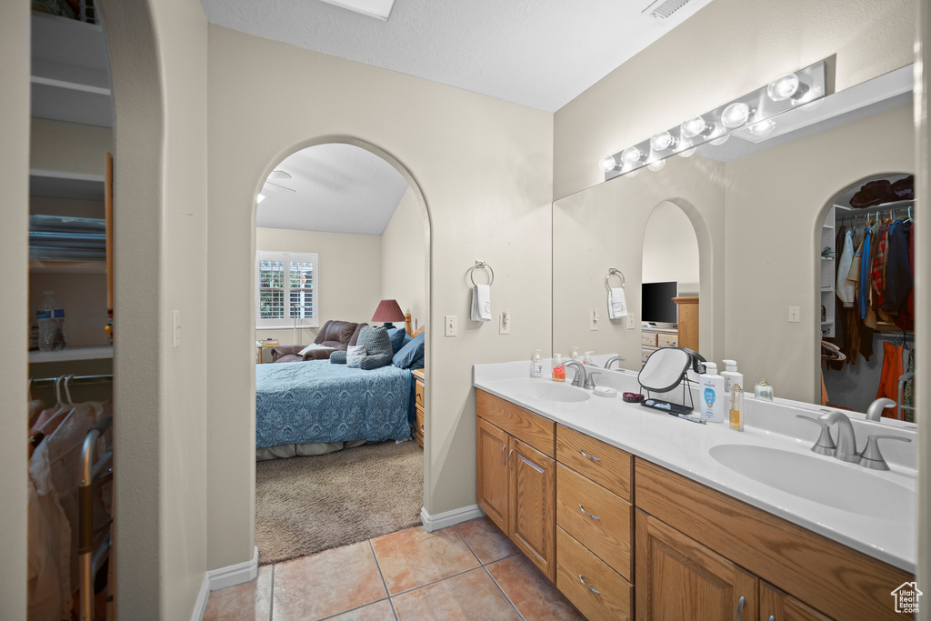 Ensuite bathroom featuring double vanity, tile patterned flooring, and a spacious closet