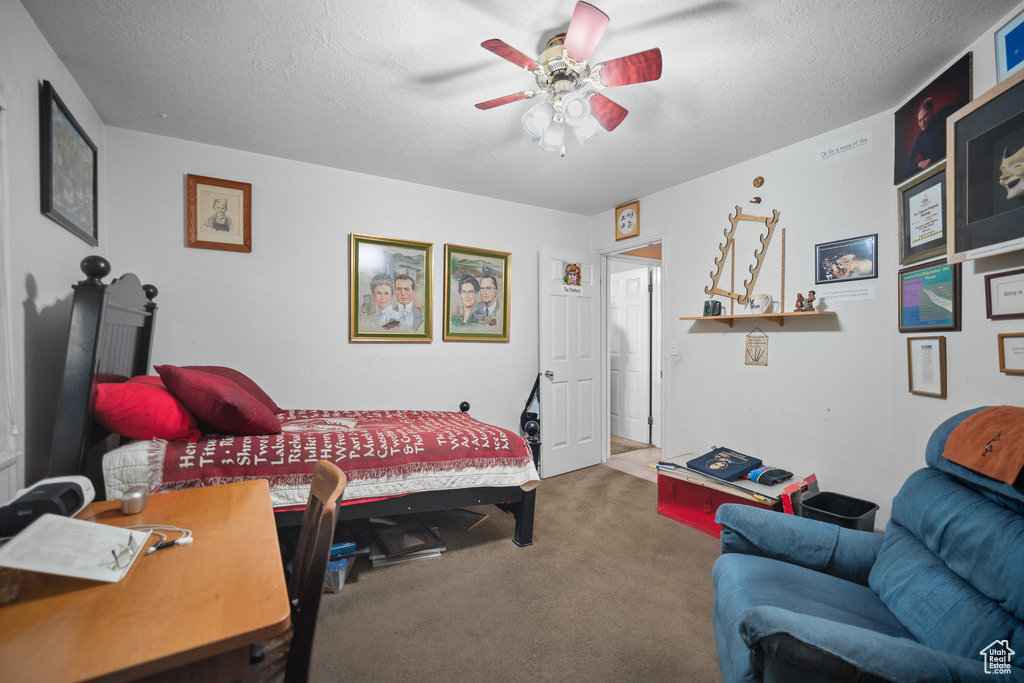 Bedroom with carpet floors, a ceiling fan, and a textured ceiling