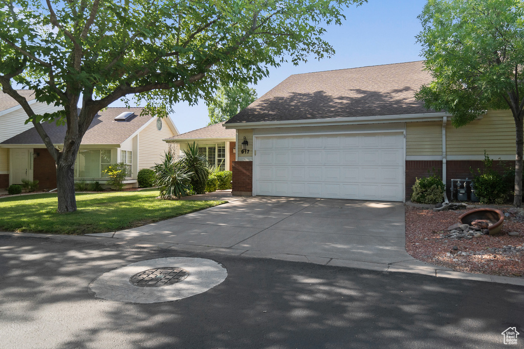 View of front of property featuring driveway, brick siding, a garage, a front yard, and a shingled roof