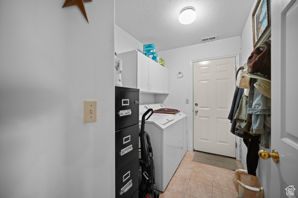 Laundry room featuring separate washer and dryer, cabinet space, a textured ceiling, and light tile patterned floors