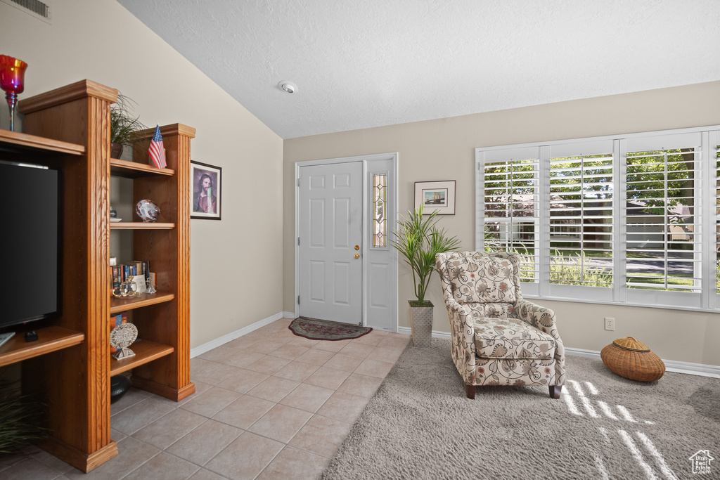 Entrance foyer with lofted ceiling, light tile patterned floors, and light colored carpet