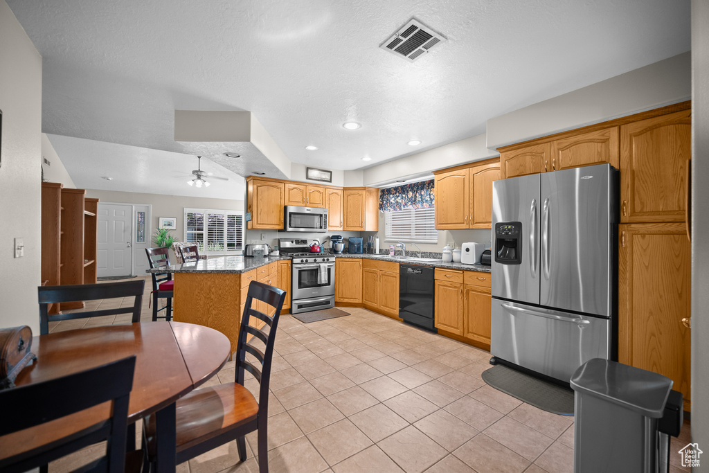 Kitchen with stainless steel appliances, light tile patterned floors, ceiling fan, a peninsula, and recessed lighting
