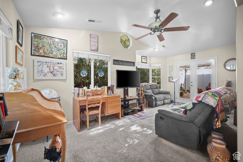 Carpeted living room featuring a ceiling fan, vaulted ceiling, and french doors