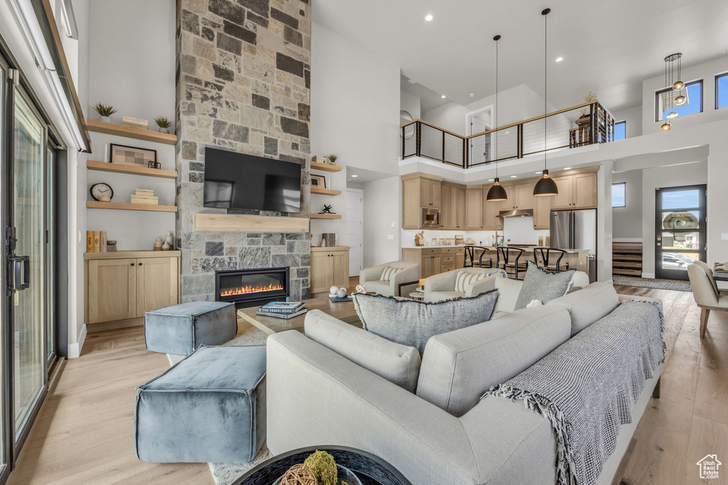 Living area featuring a high ceiling, a fireplace, light wood-type flooring, and recessed lighting