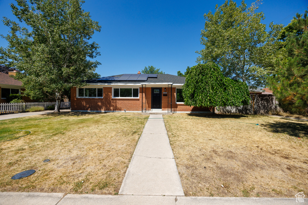 View of front of home with roof mounted solar panels and brick siding