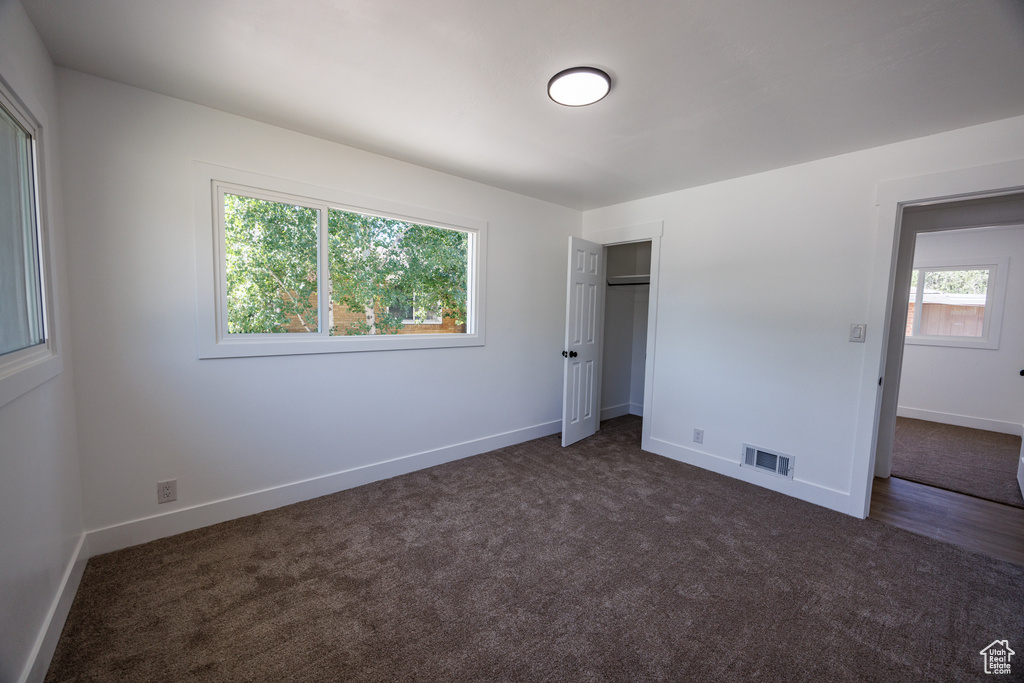 Unfurnished bedroom featuring dark colored carpet and a closet