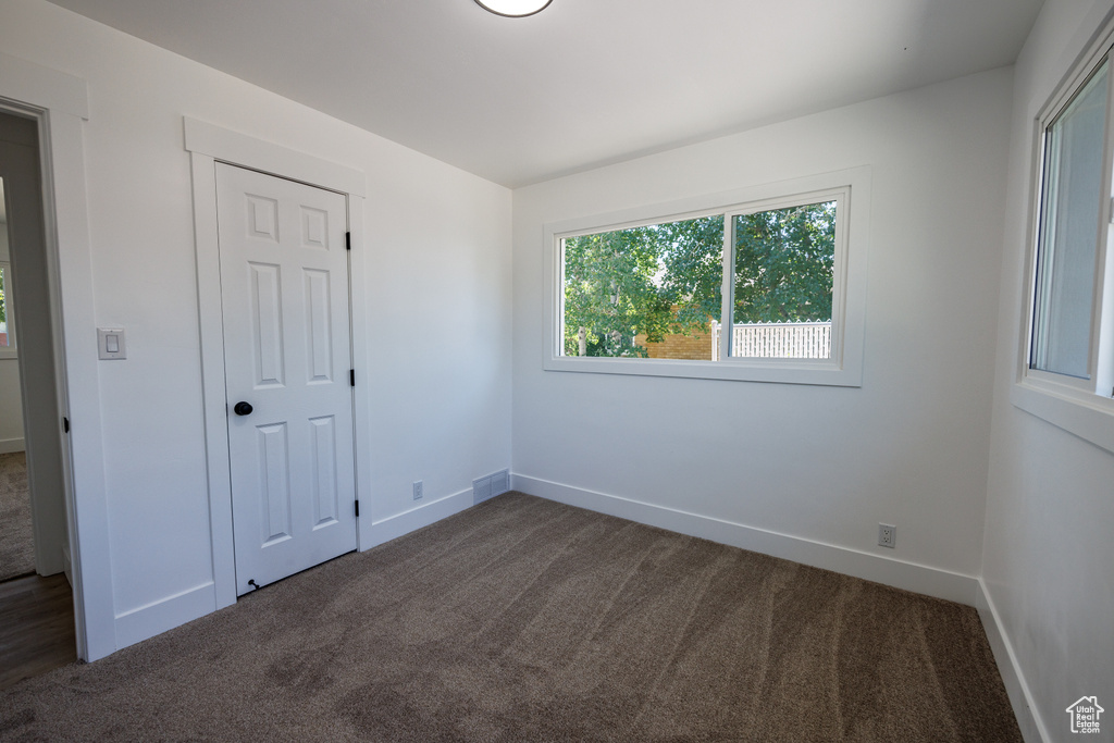 Unfurnished bedroom featuring dark carpet