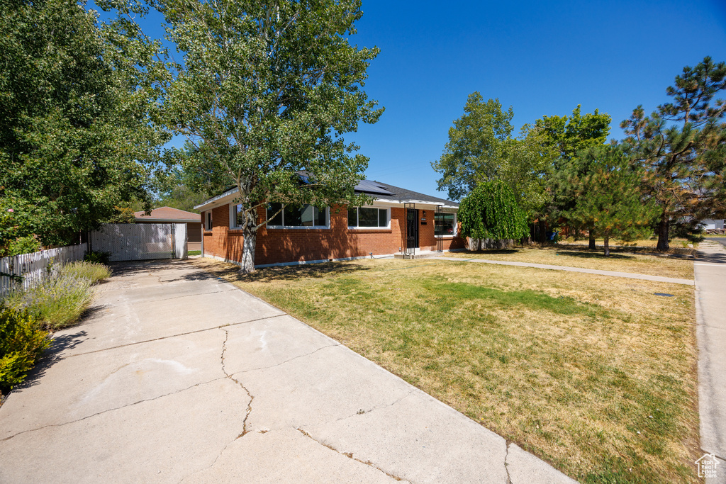 View of front facade featuring roof mounted solar panels, brick siding, a garage, and concrete driveway