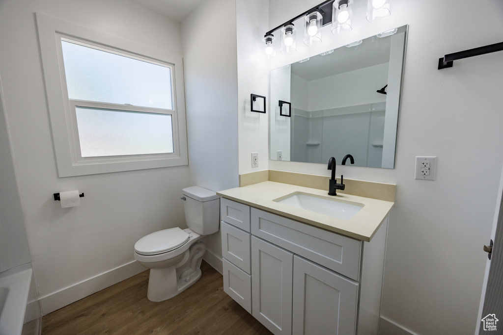 Full bath with wood finished floors, vanity, and a tub to relax in