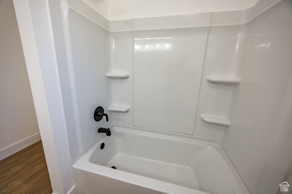 Full bath featuring wood finished floors and shower / washtub combination
