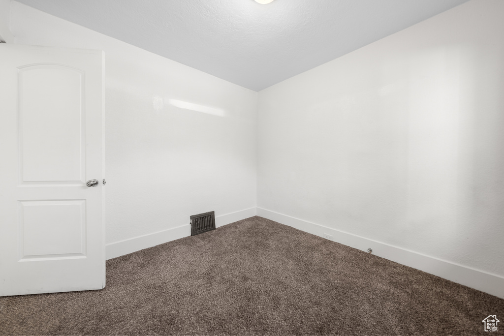 Empty room with carpet and vaulted ceiling