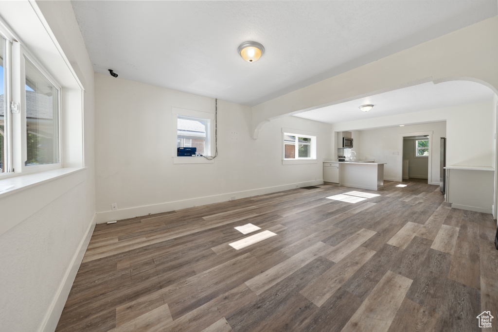 Unfurnished living room featuring arched walkways and wood finished floors